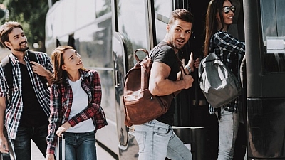 Gruppe junger Menschen steigt gut gelaunt in modernen Reisebus – Busreise mit Reisedienst Alkemeyer