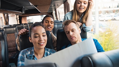 Junge Reisegruppe sitzt im Bus und plant gemeinsam die Route – entspannte Gruppenfahrt mit dem Reisedienst Alkemeyer